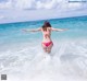 A woman in a pink bikini standing in the ocean.