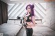 A woman with purple hair standing on a bed.