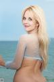 A woman in a fishnet top standing on the beach.