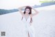 A woman in a white dress standing on a beach.