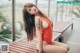 A woman in a red bathing suit sitting on a wooden bench.