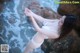 A woman in a white bikini standing on a rock by the ocean.