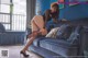 A woman in a black bodysuit and stockings sitting on a blue couch.