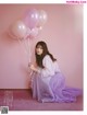 A woman sitting on the floor holding a bunch of balloons.