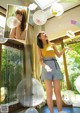 A woman in a yellow top and blue shorts blowing bubbles.