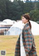 A woman standing in a field wearing a plaid coat.