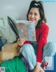 A woman sitting on a bed reading a magazine.